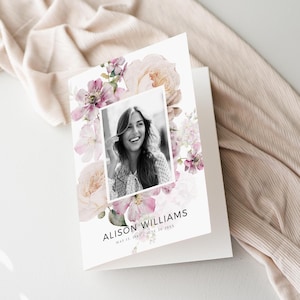 Könnte beinhalten: Eine gefaltete weiße Karte mit einem Schwarz-Weiß-Foto einer lächelnden Person, umgeben von Aquarell-Blumenillustrationen in Rosa- und Pfirsichtönen. Der Name "ALISON WILLIAMS" und Daten sind darunter gedruckt.