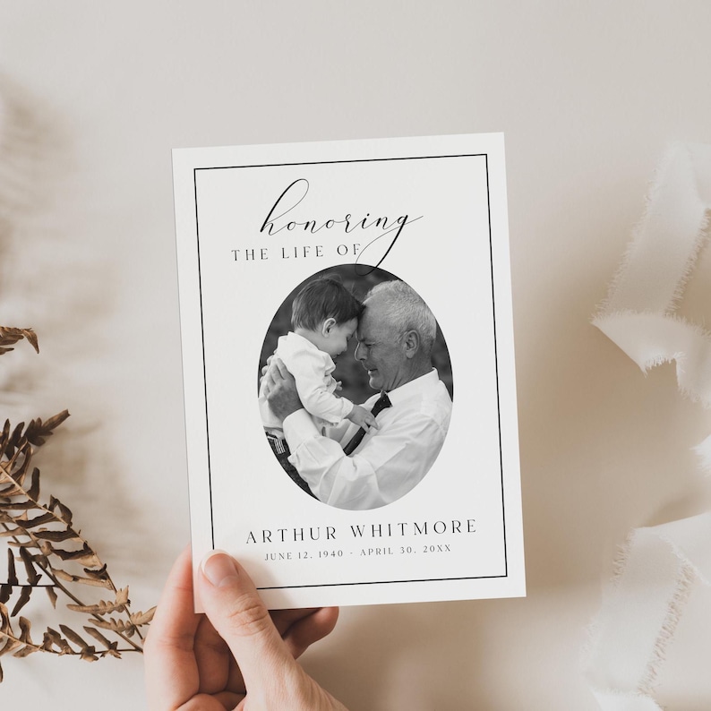 Puede incluir: Una tarjeta conmemorativa en blanco y negro con el texto "honoring the life of" sobre una foto ovalada de un hombre y un ni&ntilde;o. El nombre "Arthur Whitmore" y las fechas est&aacute;n debajo de la foto. La tarjeta est&aacute; sostenida por una mano.