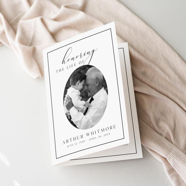 May include: A white folded funeral program card featuring a black and white oval photograph of an adult holding a child. The text reads "honoring THE LIFE OF ARTHUR WHITMORE JUNE 12, 1940 - APRIL 30, 20XX" in black serif and script fonts with a thin black border.