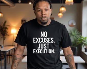 May include: Black t-shirt with the text "NO EXCUSES. JUST EXECUTION." in white. The shirt is worn by a person with dark hair and tattoos on their arms. The person is standing in front of a white surface.