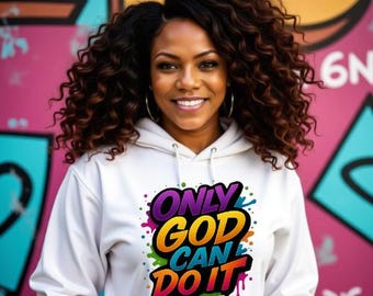May include: A woman wearing a white hoodie with the text "ONLY GOD CAN DO IT" in a colorful, graffiti-style design. The hoodie has a drawstring and a front pocket. The background features a colorful mural.
