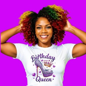 May include: A white t-shirt with the words "Birthday Queen" and a high-heeled shoe design in purple and silver. The woman in the image has colorful hair and is smiling.