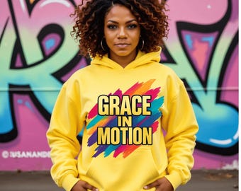 May include: A yellow hoodie with the text "GRACE IN MOTION" in a colorful design. The hoodie has a drawstring hood and a front pocket. The background features a colorful graffiti mural.