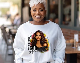 May include: White sweatshirt featuring a graphic of a woman with glasses, long hair, and the text "no worries GOD got me." The graphic is surrounded by flowers and butterflies. The person in the image is wearing the sweatshirt.