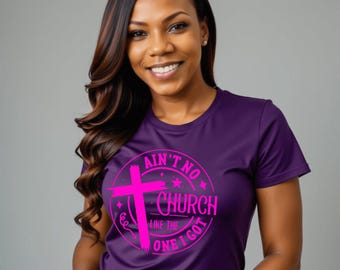 May include: A purple t-shirt with the text "Ain't No Church Like The One I Got" in a pink circular design with a cross. The shirt is worn by a person with long, dark hair.