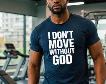 May include: Navy blue t-shirt with the white text "I DON'T MOVE WITHOUT GOD." The shirt is short-sleeved and worn by a person in a gym setting. The person is wearing a black baseball cap.