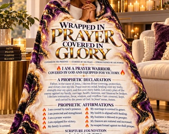 May include: A plush throw blanket featuring a purple and gold marbled border and white center. Text reads: WRAPPED IN PRAYER COVERED IN GLORY, A PROPHETIC DECLARATION, PROPHETIC AFFIRMATIONS, and SCRIPTURE FOUNDATION Isaiah 54:17 KJV with flame icons.