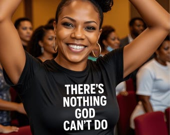 May include: A woman wearing a black t-shirt with the text "THERE'S NOTHING GOD CAN'T DO" in white lettering. She is smiling and has her arms raised.