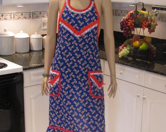 May include: A blue and red Christmas candy cane print apron with white lace trim and red ribbon bow. The apron has two pockets and a ruffled hem.