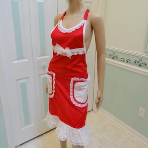 May include: Red apron with white lace trim and a white bow. The apron has two white pockets with red polka dots and a white ruffle at the bottom.