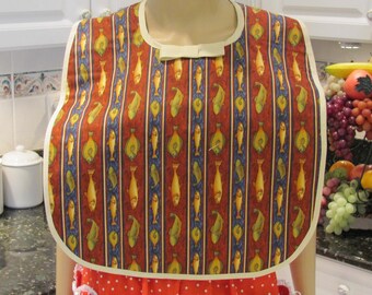 May include: A red and white striped bib with a cream colored trim and a pattern of fish. The bib is made of fabric and has a bow at the neck.