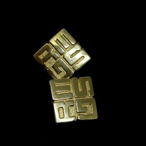 May include: Two gold-colored metal square-shaped earrings with an intricate design of interlocking squares.