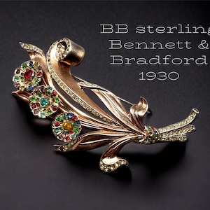 May include: A vintage sterling silver brooch with a floral design featuring multi-colored stones. The brooch is marked "BB sterling Bennett & Bradford 1930".