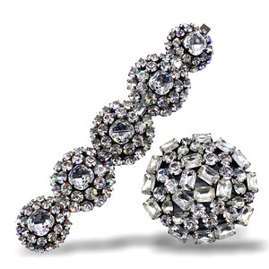 May include: A sparkling hair clip and a round brooch, both adorned with clear, faceted crystals. The hair clip features a series of crystal clusters, while the brooch showcases a dense arrangement of various crystal shapes. The jewelry is set against a white background.