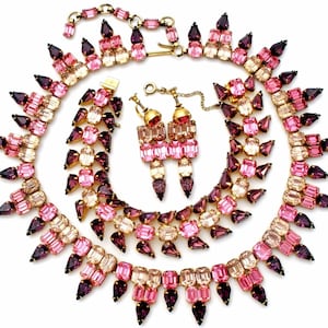 May include: A vintage pink and purple rhinestone necklace, bracelet and earrings set. The jewellery features graduated teardrop and rectangular shaped rhinestones.