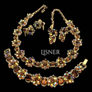 Könnte beinhalten: Ein goldfarbenes Halsketten- und Armbandset mit braunen, schillernden Strasssteinen. Das Set enthält ein Paar passende Ohrringe. Der Schmuck ist mit "LISNER" gekennzeichnet.