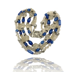 Op de afbeelding: Een meerrijige ketting met heldere en blauwe glazen kralen, zilveren accenten en een zilveren sluiting.