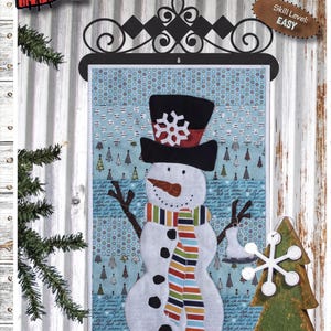 May include: A quilt pattern titled MR. FROSTY measuring 12 inches by 18 inches. The design features a snowman wearing a black top hat with a white snowflake, a multi-colored striped scarf, and black buttons on a light blue background with trees.