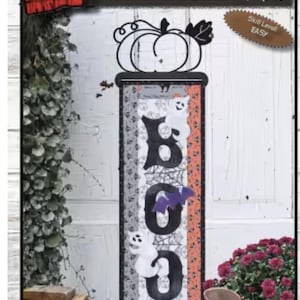 May include: A craft pattern titled Halloween Bat 'N Boo's, measuring 6 inches by 18 inches. The design features a black pumpkin topper, a vertical banner with the word BOO in large black letters, white ghost figures, a purple bat, and spiderweb patterns.