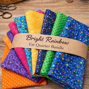 May include: A bundle of colorful fat quarters, featuring a variety of patterns and colors, including polka dots and floral designs. The bundle is wrapped with a brown paper band that reads "Bright Rainbow Fat Quarter Bundle."