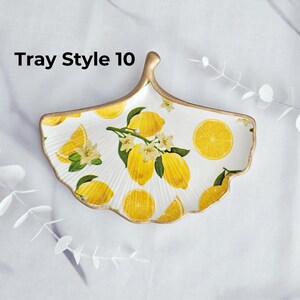 May include: White ceramic serving tray in a leaf shape, decorated with yellow lemons, green leaves, and white blossoms. The tray has a gold-colored rim and the text "Tray Style 10".