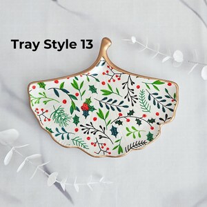 May include: A white, leaf-shaped decorative tray with a gold rim and handle. The tray is decorated with a pattern of green leaves and red berries. The text "Tray Style 13" is printed on the top left.