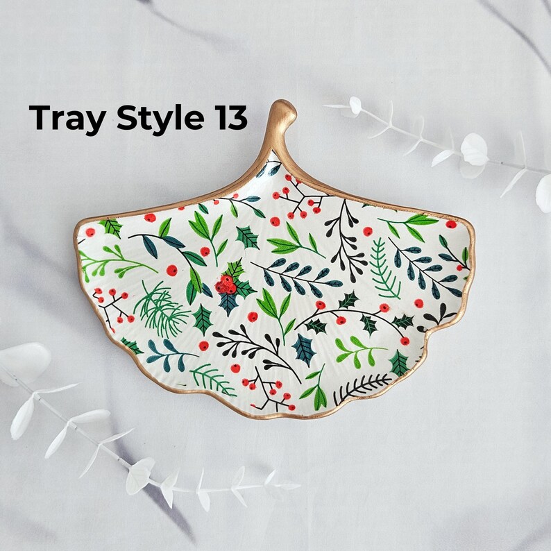 May include: A white, leaf-shaped decorative tray with a gold rim and handle. The tray is decorated with a pattern of green leaves and red berries. The text "Tray Style 13" is printed on the top left.