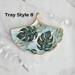 May include: Ginkgo leaf-shaped decorative tray with a gold rim. The tray features a tropical leaf pattern in shades of green and blue on a white background. The text "Tray Style 8" is visible on the upper left.