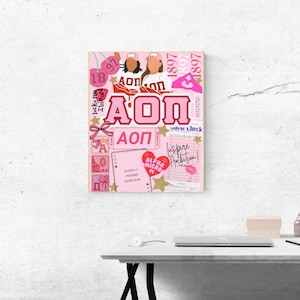 May include: A pink collage-style print featuring the Greek letters AOP, various text elements, and illustrations. The design includes hearts, stars, and the words "Inspire Ambition". The color scheme is primarily pink and white.