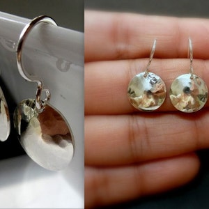 May include: A pair of silver dangle earrings with hammered round disc pendants.