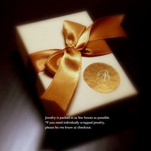 May include: A white gift box with a gold ribbon tied in a bow. The box has a gold sticker with the letter "B" on it. The text on the box reads: "Jewelry is packed in as few boxes as possible. *If you need individually wrapped jewelry, please let me know at checkout."