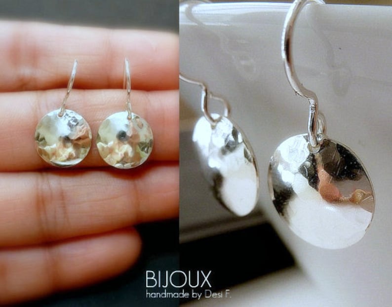 May include: A pair of silver earrings with hammered round discs. The earrings have a simple, minimalist design.