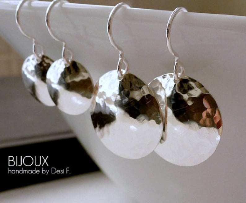 May include: Three pairs of silver hammered disc earrings with a simple hook closure. The earrings are a light silver color and have a textured, hammered finish.