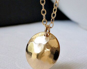 May include: A gold necklace with a hammered, round pendant. The pendant is about 1/2 inch in diameter. The necklace is called "Soleil" and is made of gold.