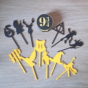 Può includere: Una collezione di decorazioni per torte a tema Harry Potter gialle e nere. Le decorazioni includono lo stemma di Hogwarts, un cervo, un serpente, il simbolo dei Doni della Morte e l'insegna del binario 9 3/4.