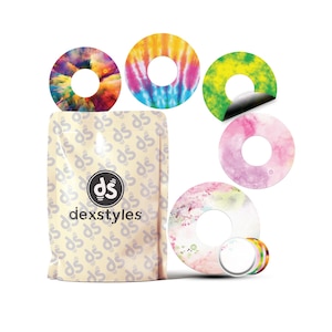 Puede incluir: Un conjunto de parches adhesivos circulares y coloridos con varios diseños, incluyendo tie-dye y estampados florales. También se muestra un paquete de parches "dexstyles". Los parches están diseñados para ser aplicados a un dispositivo médico.