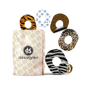 Op de afbeelding: Een selectie van dierenprints, waaronder tijgerstrepen, luipaardvlekken en zebra strepen, naast een blauw bloemenpatroon. De ontwerpen worden gepresenteerd op een witte achtergrond. De verpakking is beige en van het merk "dexstyles".