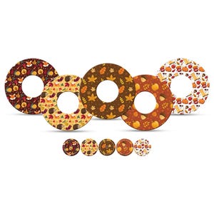 May include: A collection of five circular coasters and five smaller coasters, each with a unique autumn-themed pattern. Designs include leaves, foxes, hedgehogs, and pumpkins in shades of brown, orange, and yellow.