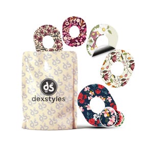 Könnte beinhalten: Eine Packung Dexstyles-Produkte mit verschiedenen floralen Mustern. Die Designs umfassen rote, rosa und weiße Blumen auf marineblauem Hintergrund sowie andere Blumenmuster in Burgunderrot, Creme und Weiß. Die Verpackung ist beige mit dem Dexstyles-Logo.