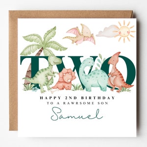 May include: A square birthday card featuring a dinosaur-themed illustration. The design includes the word "TWO" in dark green, dinosaurs, palm trees, and the text "HAPPY 2ND BIRTHDAY TO A RAWSOME SON" with a name in script.