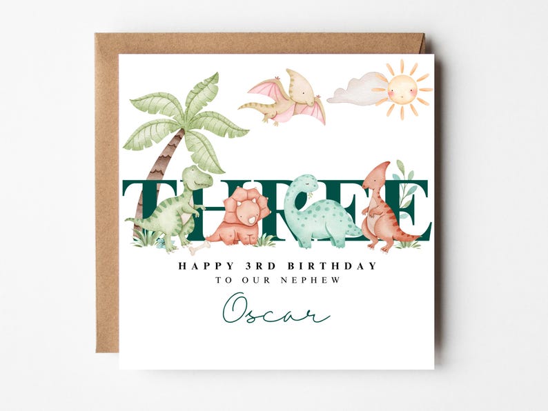 May include: A birthday card with a brown envelope. The card features a watercolour illustration of dinosaurs, a palm tree, and a sun. Text reads "THREE", "HAPPY 3RD BIRTHDAY TO OUR NEPHEW", and "Oscar".