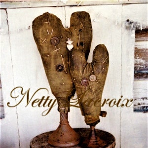 May include: Two brown fabric oven mitts with buttons and pins, displayed on a brown and gold patterned box with a white background.