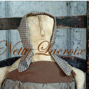 May include: A handmade rag doll wearing a brown and white checked dress, a blue and white checked bonnet, and with a painted face. The doll is sitting in a wooden rocking chair.