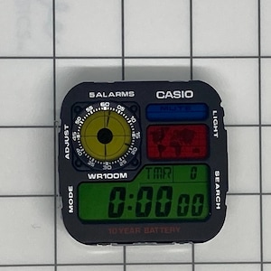 May include: Black Casio digital watch face with multiple displays. Features include a yellow dial, a red world map, and a green digital time display. Text includes "5 ALARMS", "CASIO", "WR100M", and "10 YEAR BATTERY".