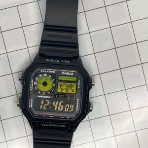 Pu&ograve; includere: Orologio digitale Casio nero con cinturino nero. Il quadrante dell'orologio mostra l'ora, la data e il giorno della settimana. Ha anche una funzione di ora mondiale, allarmi e una batteria da 10 anni.