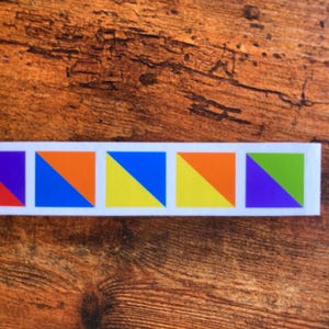 May include: A row of five colorful triangular patches, each with a different color combination. The patches are red and purple, orange and blue, yellow and blue, yellow and orange, and purple and green.
