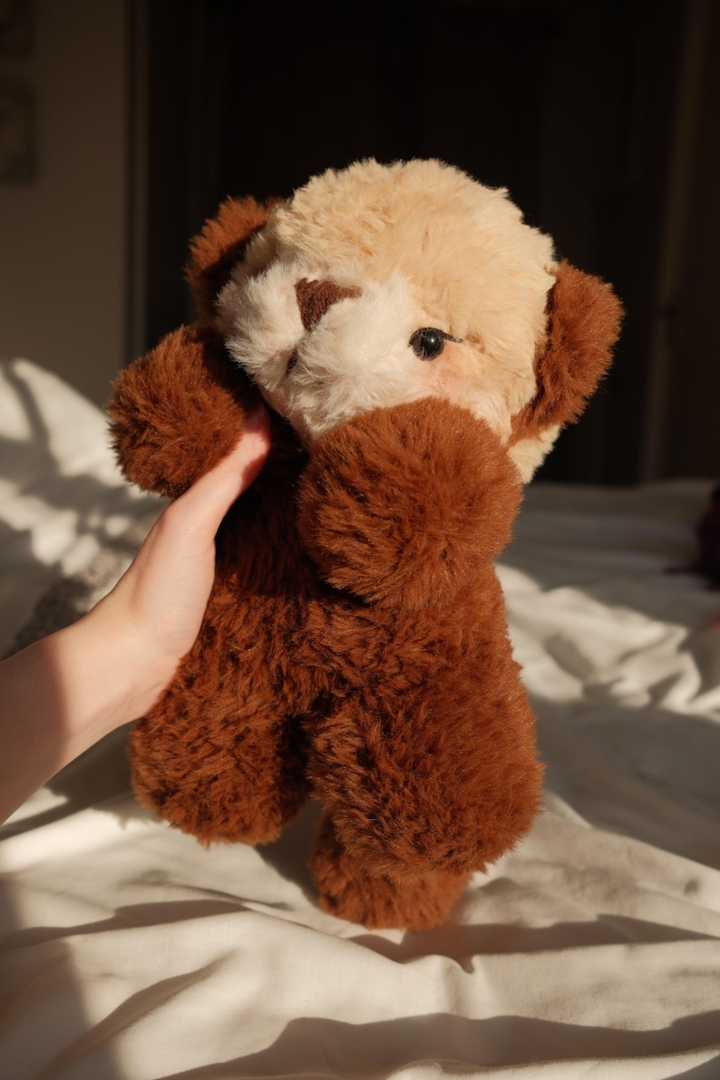 Puede incluir: Un oso de peluche con cuerpo marr&oacute;n oscuro y cabeza de color beige claro en contraste. El juguete tiene orejas peque&ntilde;as y redondeadas, una nariz cosida en marr&oacute;n oscuro y ojos oscuros. La textura del pelaje es suave y esponjosa.