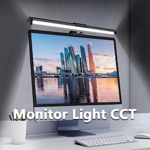 May include: A black monitor light bar is mounted above a computer monitor. The light bar is turned on, illuminating the screen. The monitor displays a cityscape. The text "Monitor Light CCT" is displayed on the bottom of the monitor.