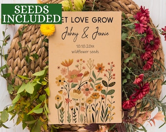 以下が含まれることがあります： 「LET LOVE GROW」の文字と「Johnny & Jennie」の名前、日付と「wildflower seeds」が書かれたベージュ色のカード。オレンジ、ピンク、黄色の花柄イラストが描かれています。「SEEDS INCLUDED」の文字が緑色のボックスに入っています。