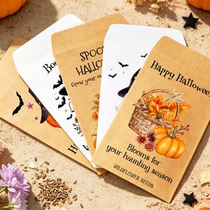 May include: Four rectangular paper seed packets arranged in a fan shape. The packets feature Halloween-themed illustrations including pumpkins, a basket of autumn leaves, bats, and a witch hat, with text reading Happy Halloween and Blooms for your haunting season.